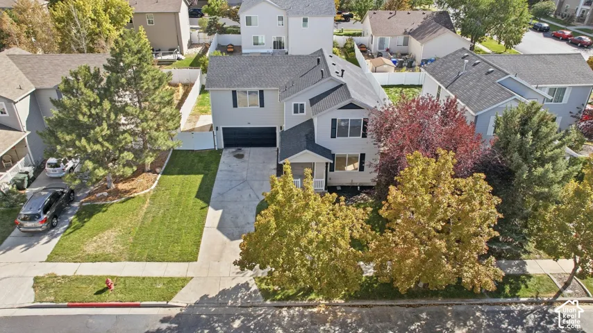 Two-story residential architecture with an attached garage, featuring a concrete driveway and mature trees