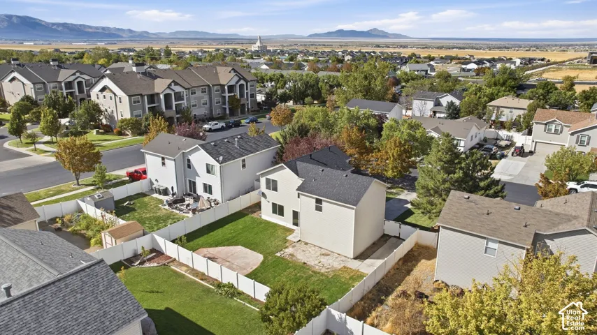Expansive backyard with a manicured lawn, established trees, and white privacy fencing