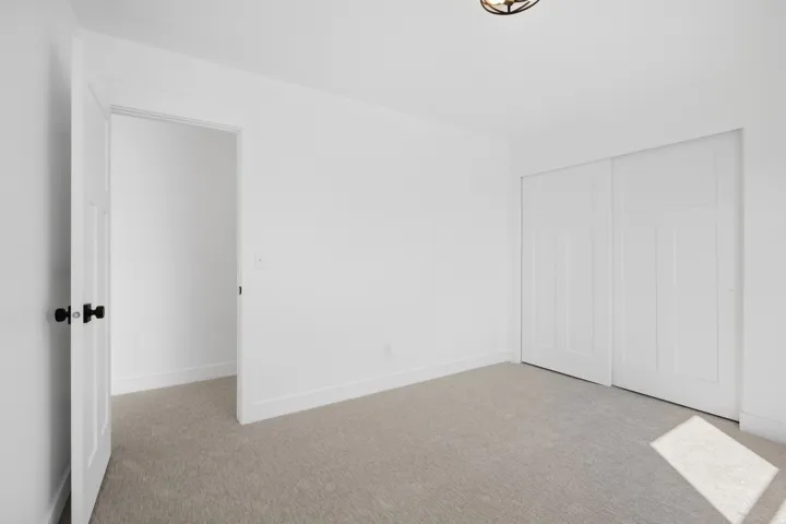 Neutral-toned carpeting, white walls, and a contemporary semi-flush ceiling fixture