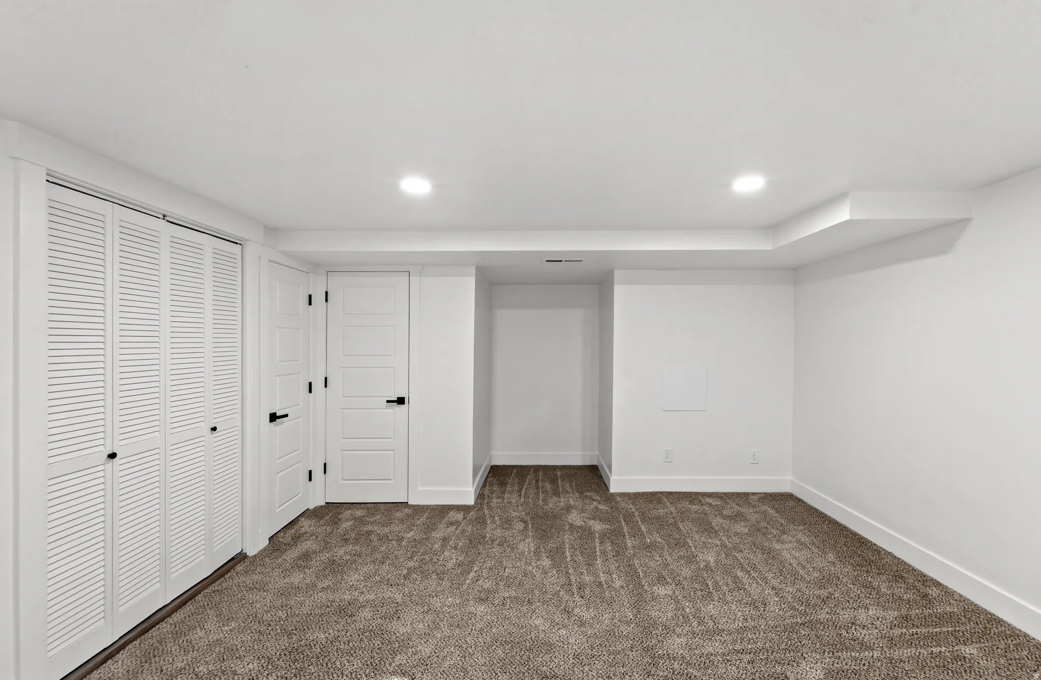 Recessed lighting, louvered bi-fold doors, paneled interior doors, dark bronze hardware, and neutral carpet flooring