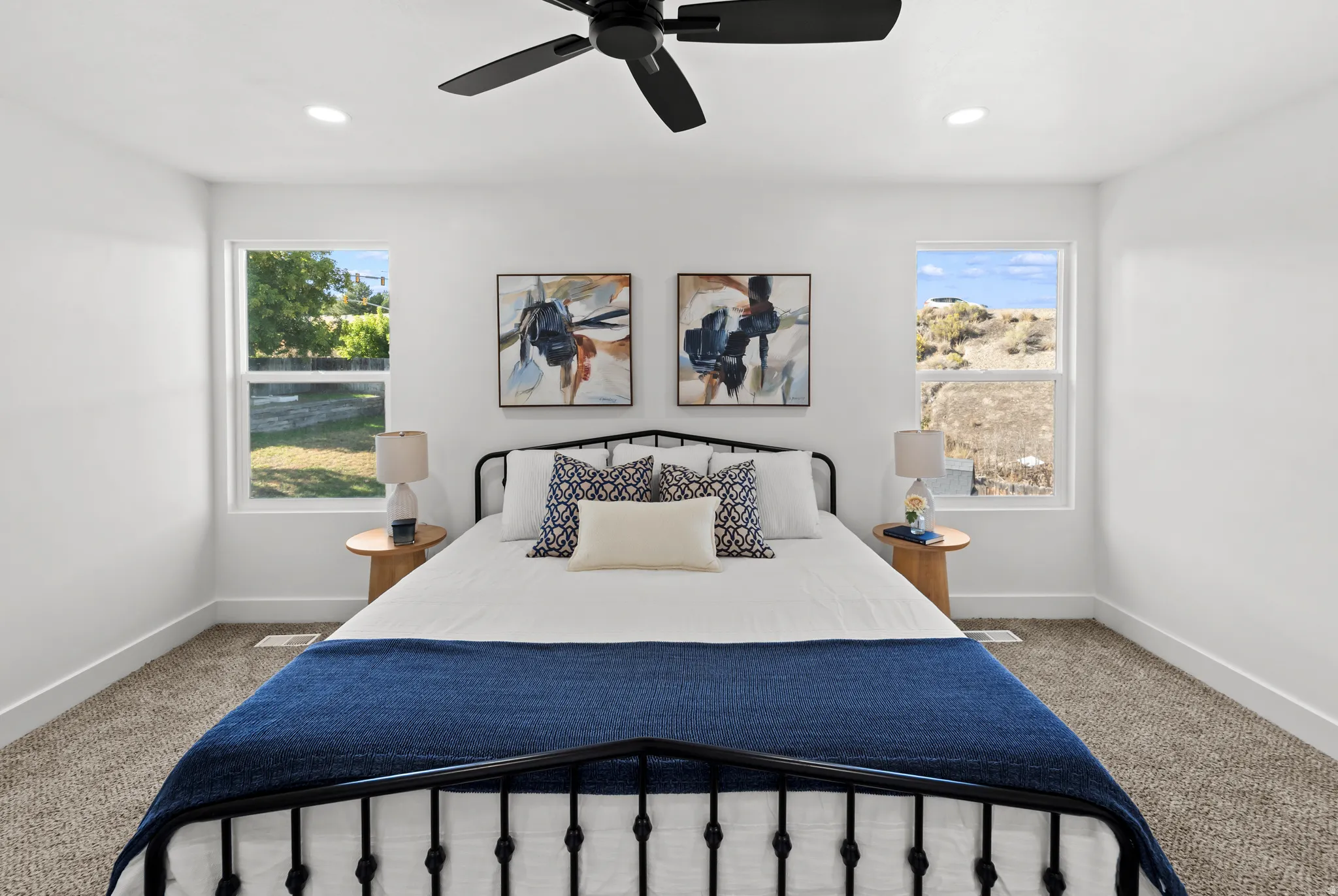 Spacious room featuring a black metal bed frame, plush carpeting, recessed lighting, and a ceiling fan