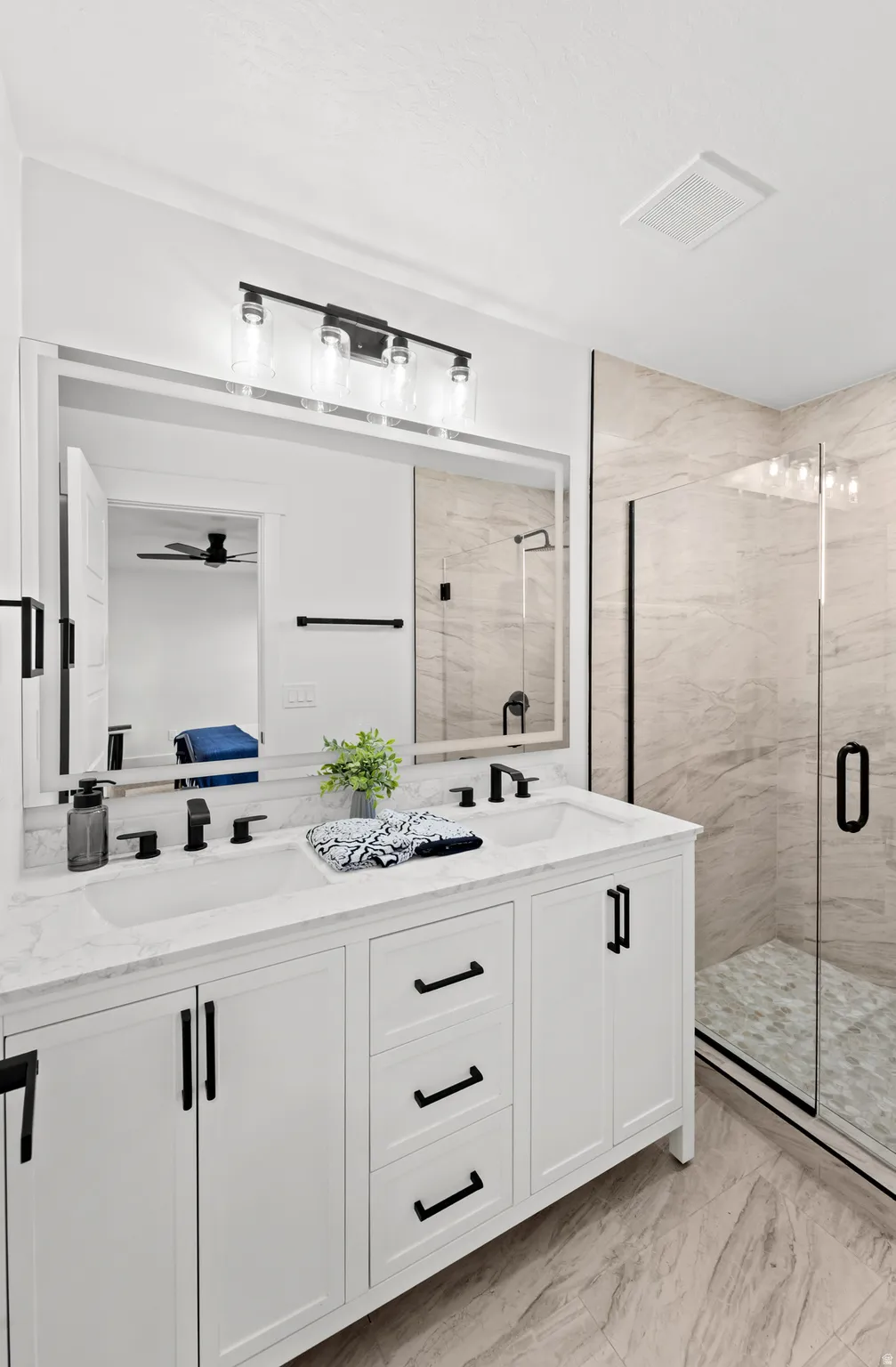 Dual vanity with white cabinetry, matte black hardware, and a stone countertop