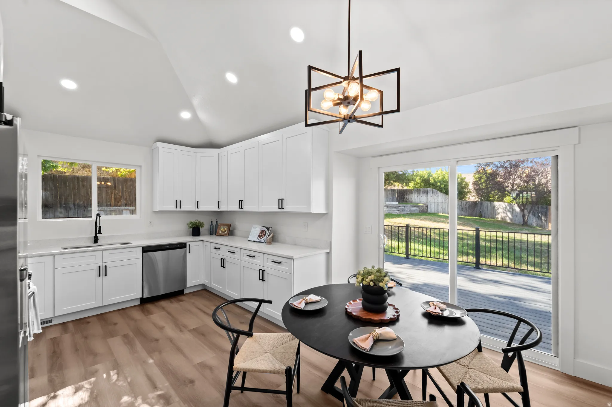 Kitchen featuring white cabinetry, stainless steel appliances, wood-finish flooring, and sliding glass doors opening to an exterior deck