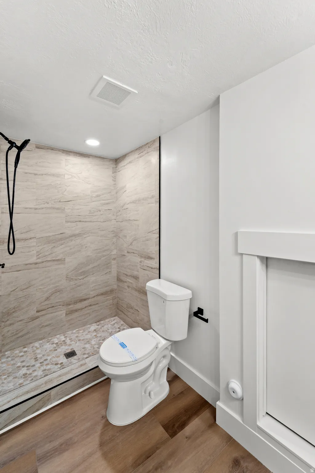 Walk-in shower with natural stone-look wall tile and a pebble floor