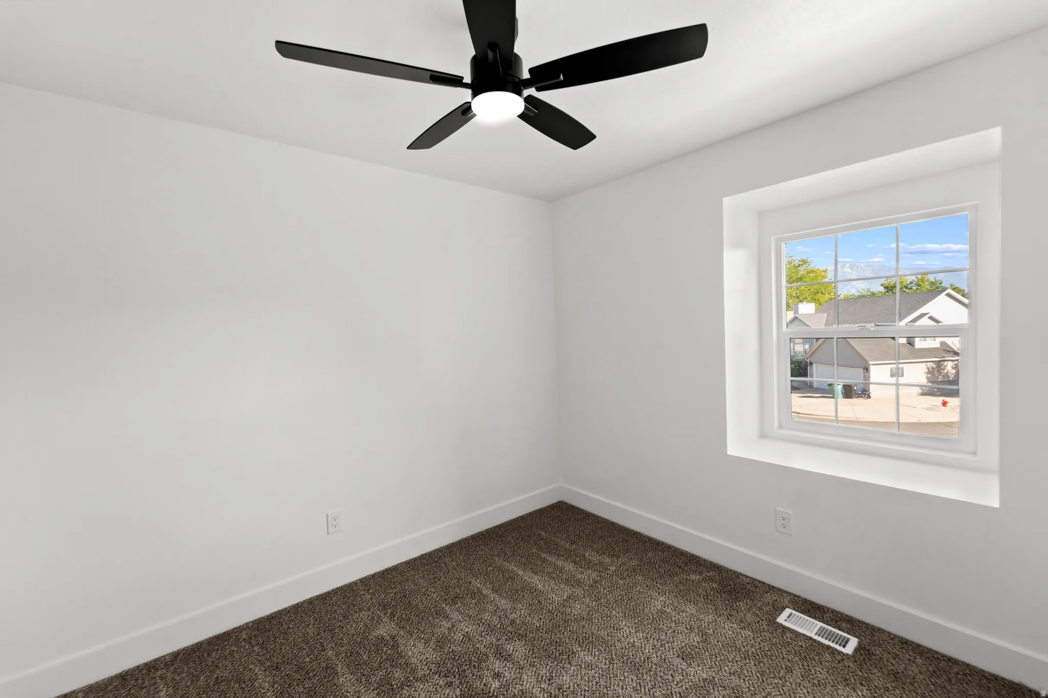 Neutral wall paint, ceiling fan with integrated lighting, carpeted flooring, and a double-hung window
