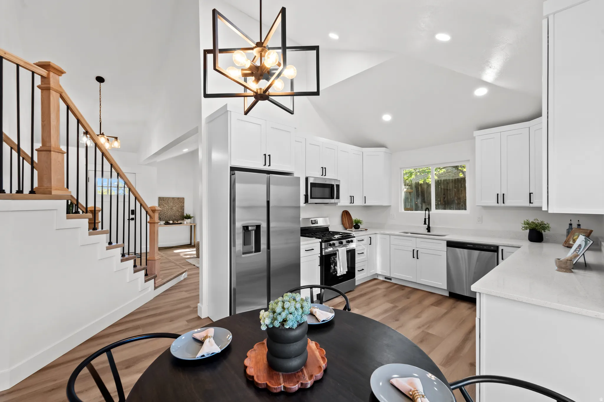 Kitchen featuring white cabinetry, stainless steel appliances, and a vaulted ceiling with recessed lighting