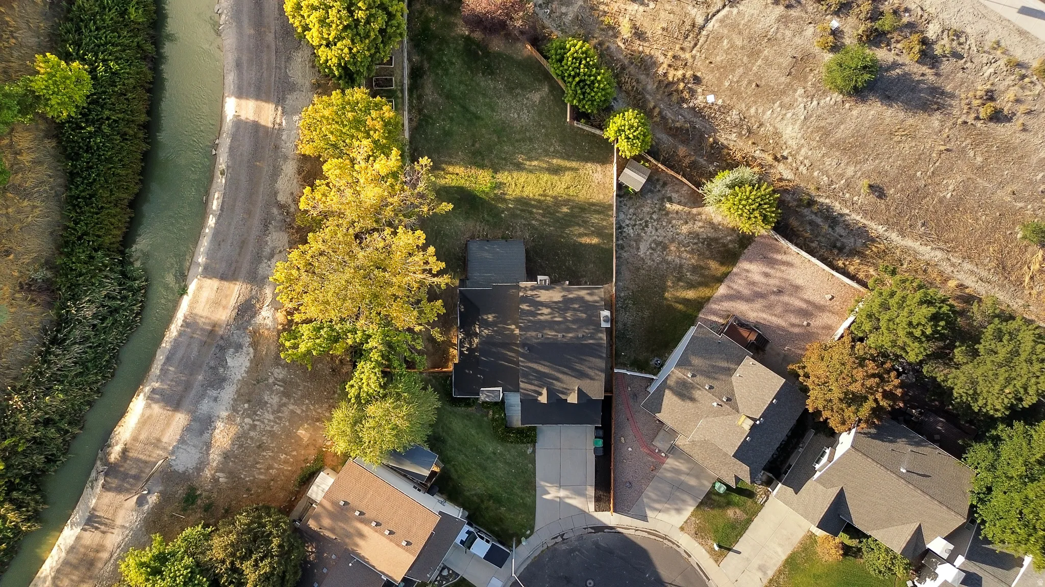 Property featuring a cul-de-sac location, paved driveway, mature trees, and canal access