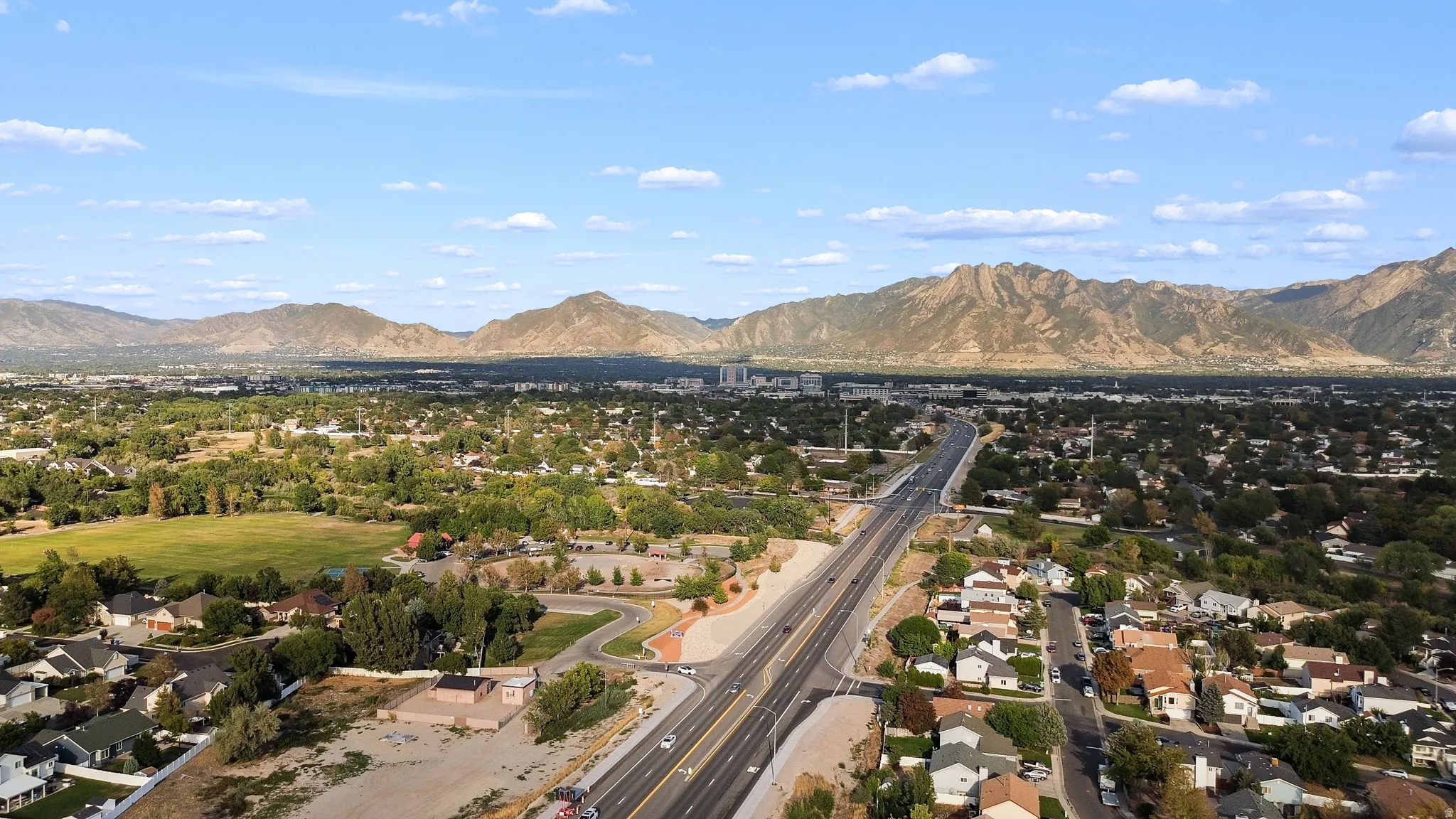 Expansive regional setting featuring residential areas, substantial green spaces, and a prominent highway