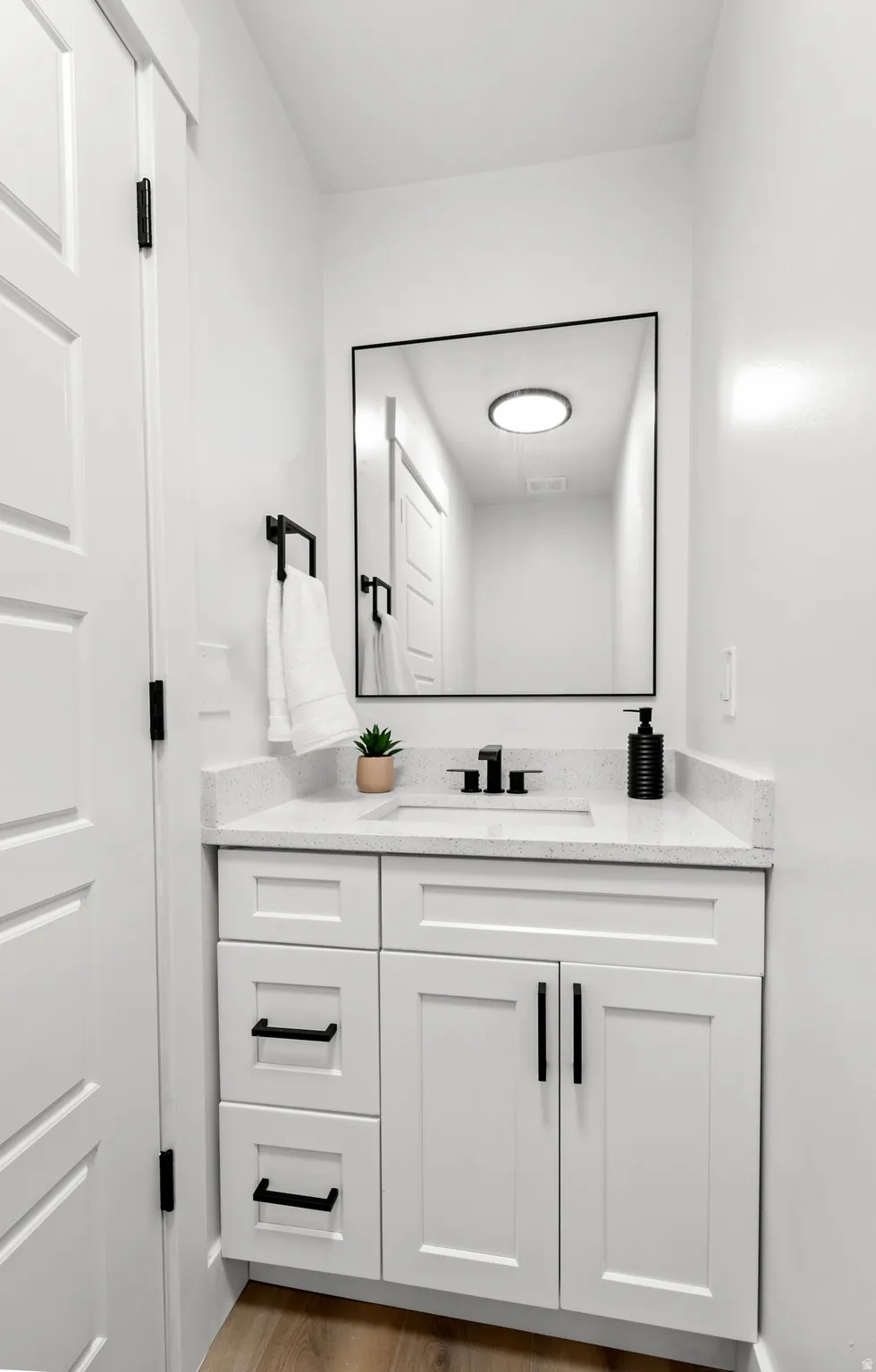 White shaker-style vanity with matte black hardware, integrated sink, and light-toned countertop