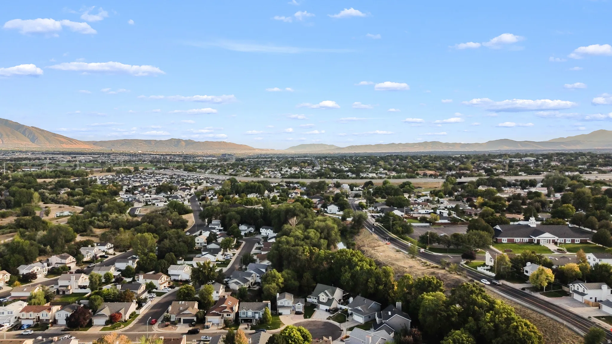 Expansive neighborhood with diverse residential architecture and mature trees, set against a backdrop of distant mountains