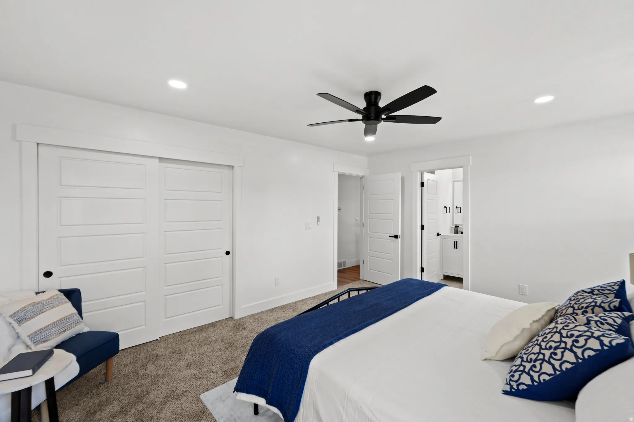 Recessed lighting, ceiling fan, carpet flooring, white sliding closet doors, and contrasting dark hardware