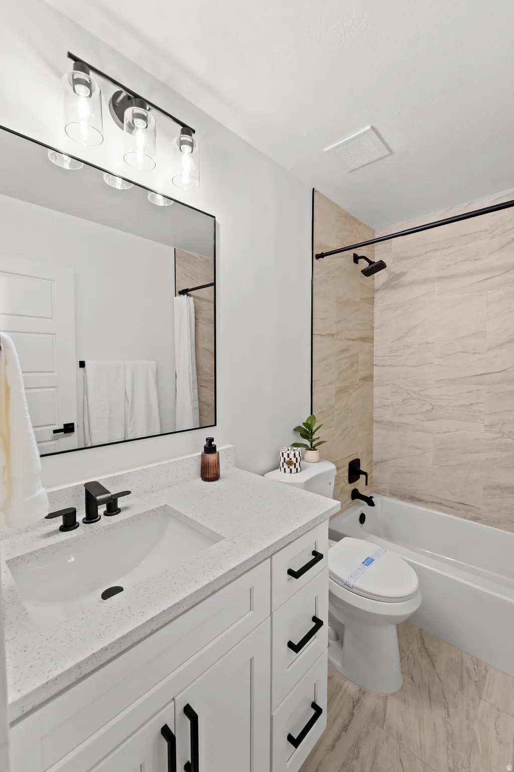 White vanity with black hardware, integrated rectangular sink, and speckled countertop