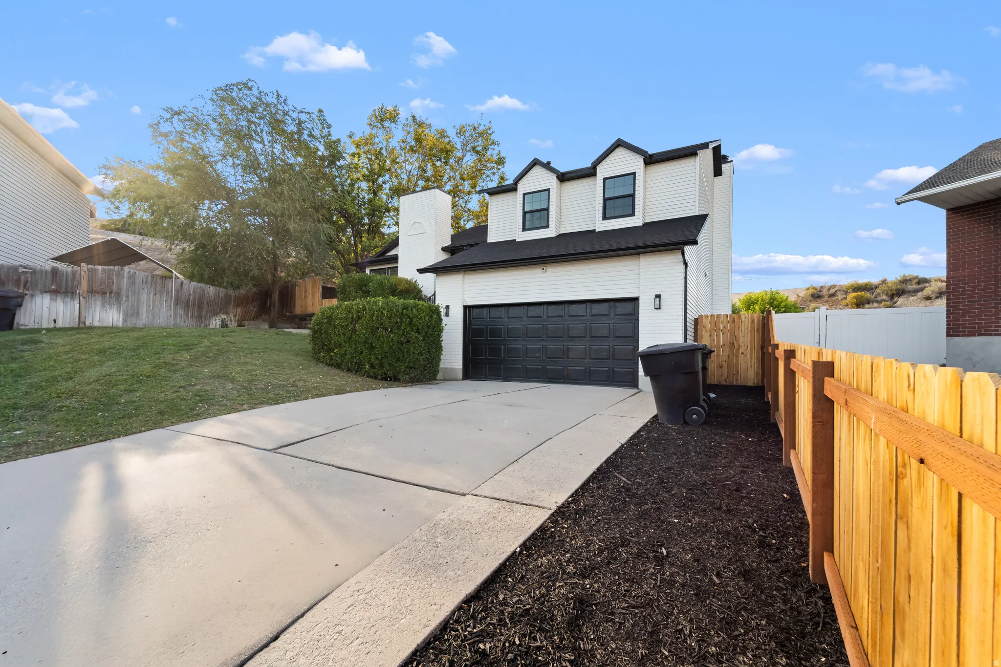 White siding exterior with black trim accents and a black garage door