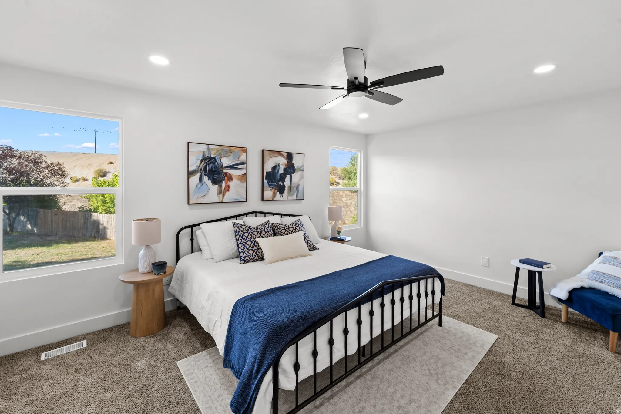 Recessed lighting, ceiling fan, two windows, and neutral carpet