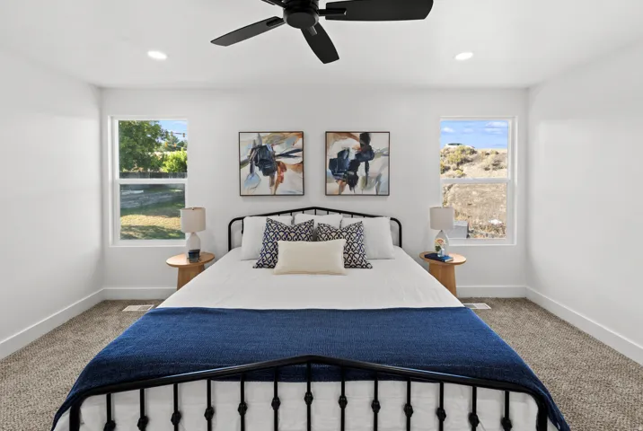 Spacious room featuring a black metal bed frame, plush carpeting, recessed lighting, and a ceiling fan