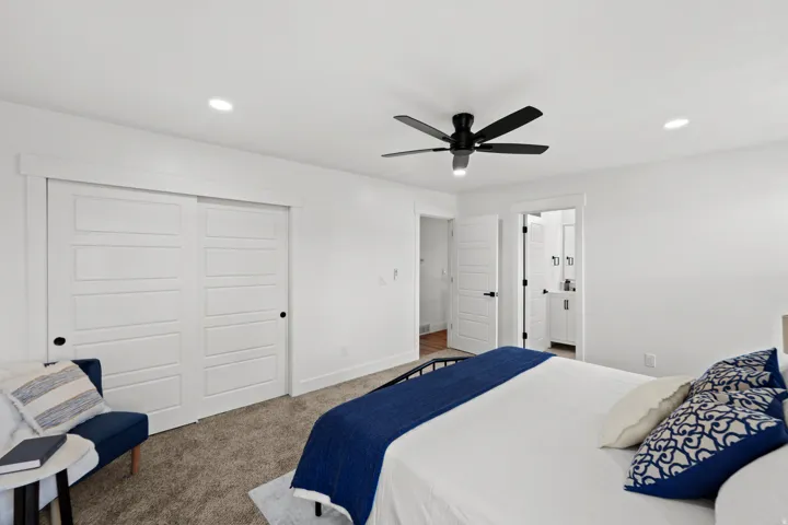 Recessed lighting, ceiling fan, carpet flooring, white sliding closet doors, and contrasting dark hardware