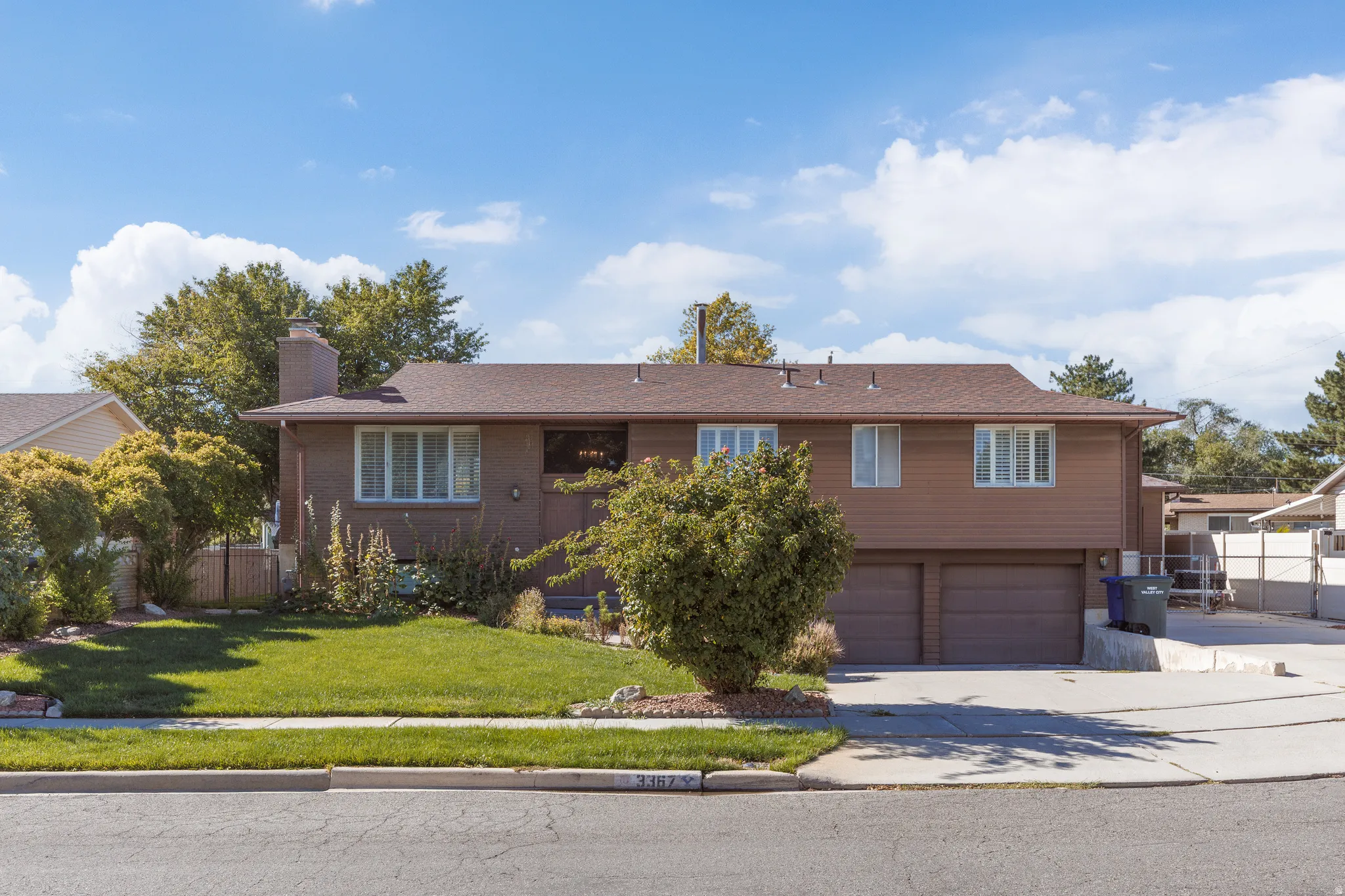 Brick and siding exterior with a brown shingle roof, featuring a two-car garage, mature landscaping, and an established lawn