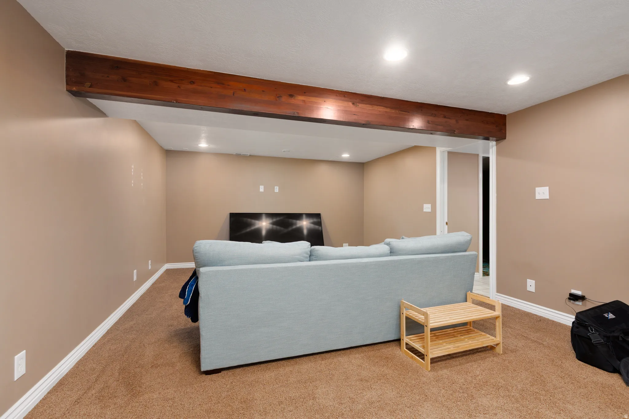 Exposed wood beam accenting a neutral wall palette and recessed lighting