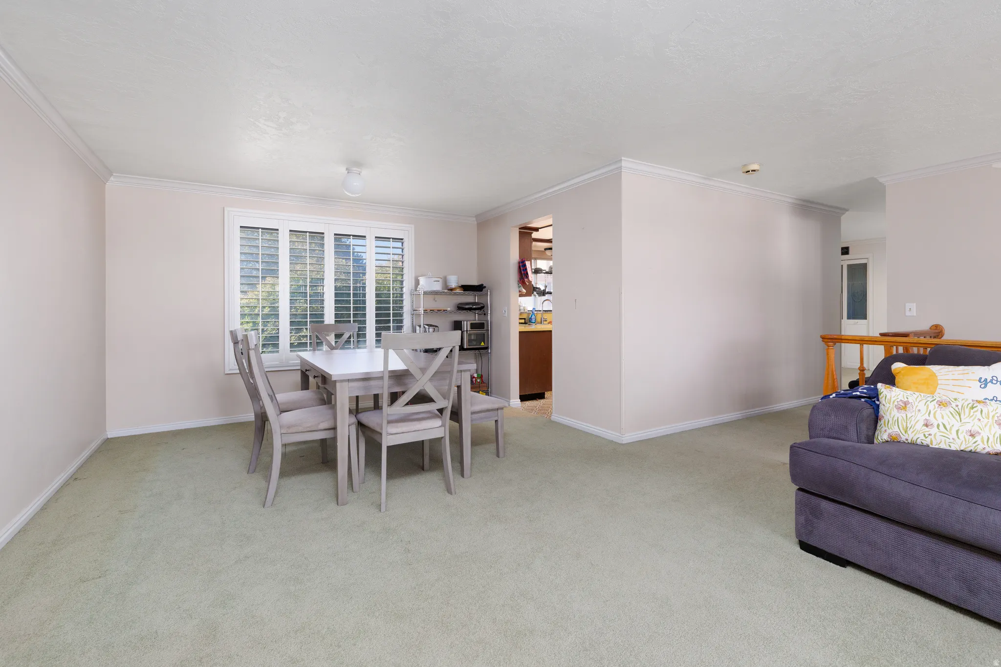 Light-toned wall finishes, crown molding, and a visible window with louvered shutters