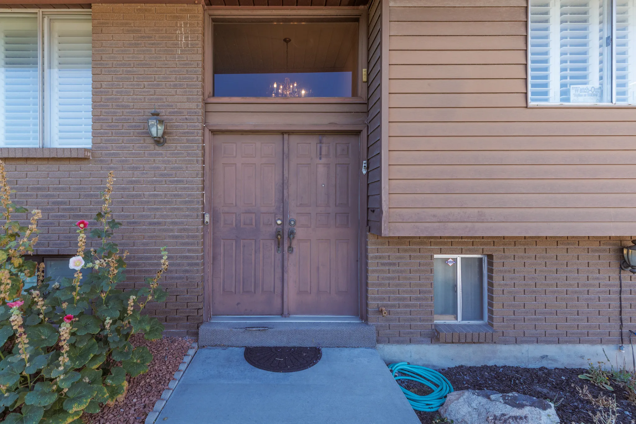 Brick and siding exterior with a double-door entry, transom window, and exterior wall sconces