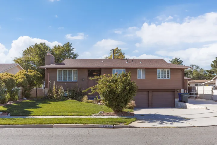 Brick and siding exterior with a brown shingle roof, featuring a two-car garage, mature landscaping, and an established lawn