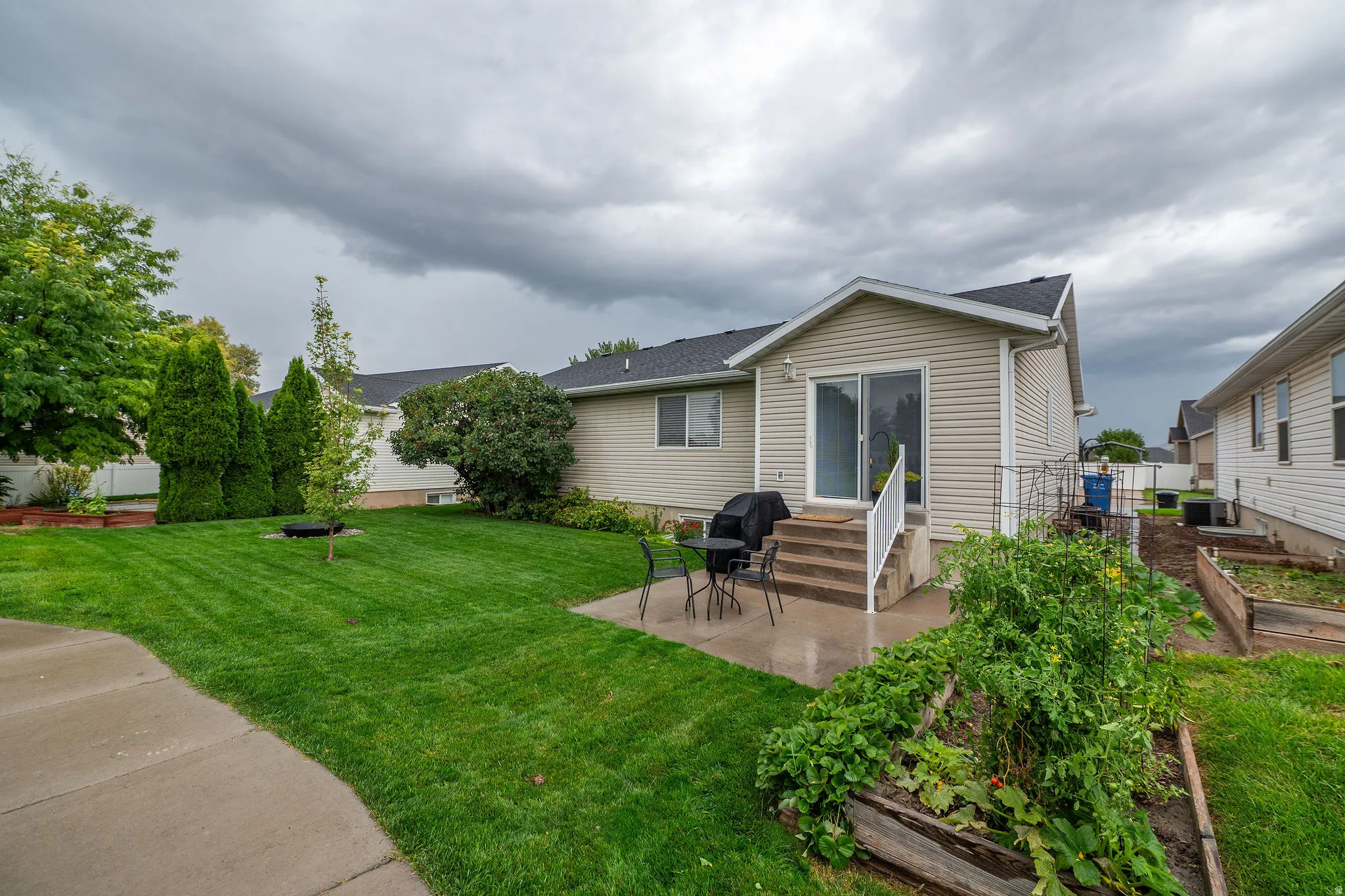 Backyard featuring a concrete patio, sliding glass door access, exterior stairs with white railings, and a manicured lawn