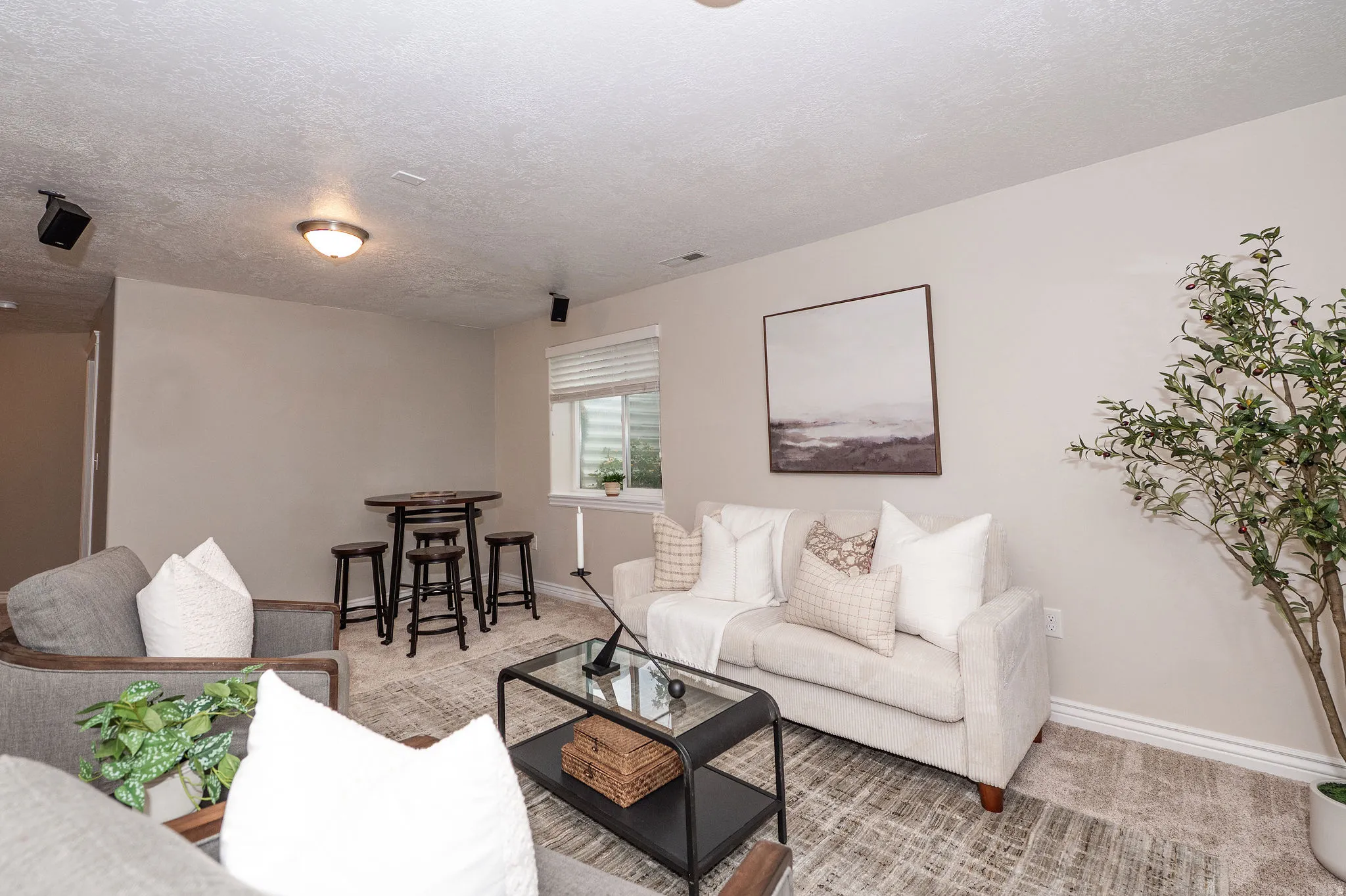 Neutral-toned walls, recessed lighting, wall-mounted speakers, and a window with blinds