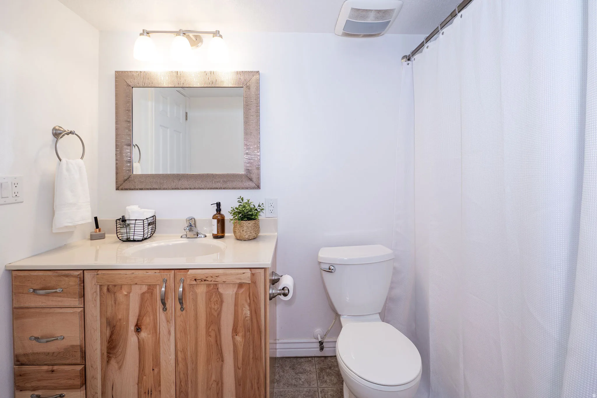 Bathroom featuring a single vanity with wood-finish cabinetry, a built-in sink, and a light-toned countertop