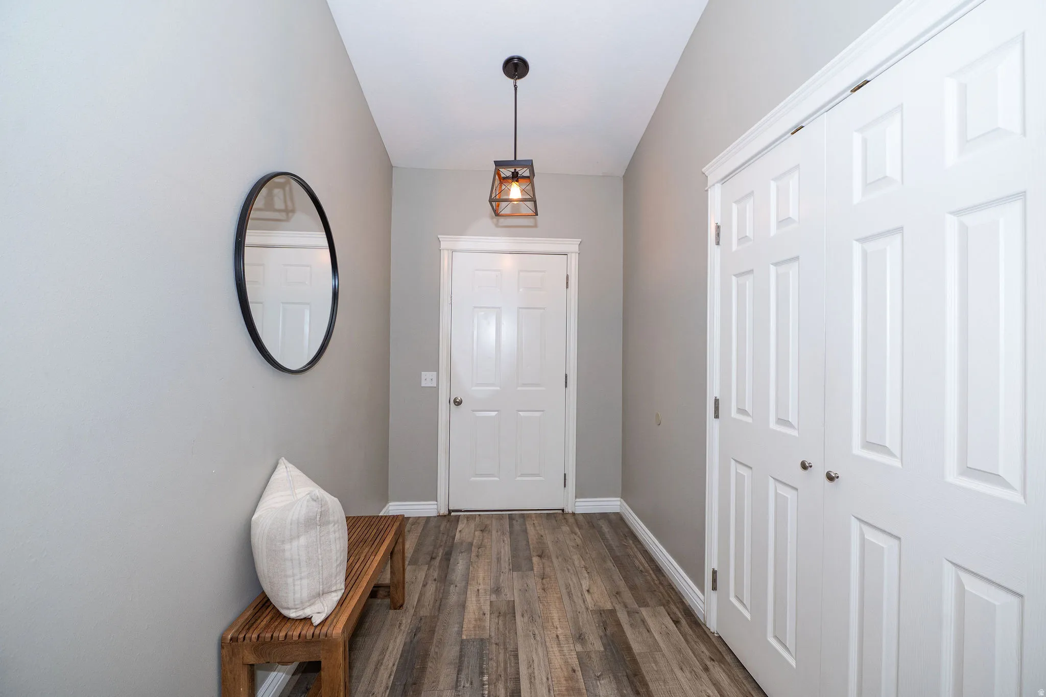 Wood-finish flooring, white paneled doors, and a decorative ceiling fixture