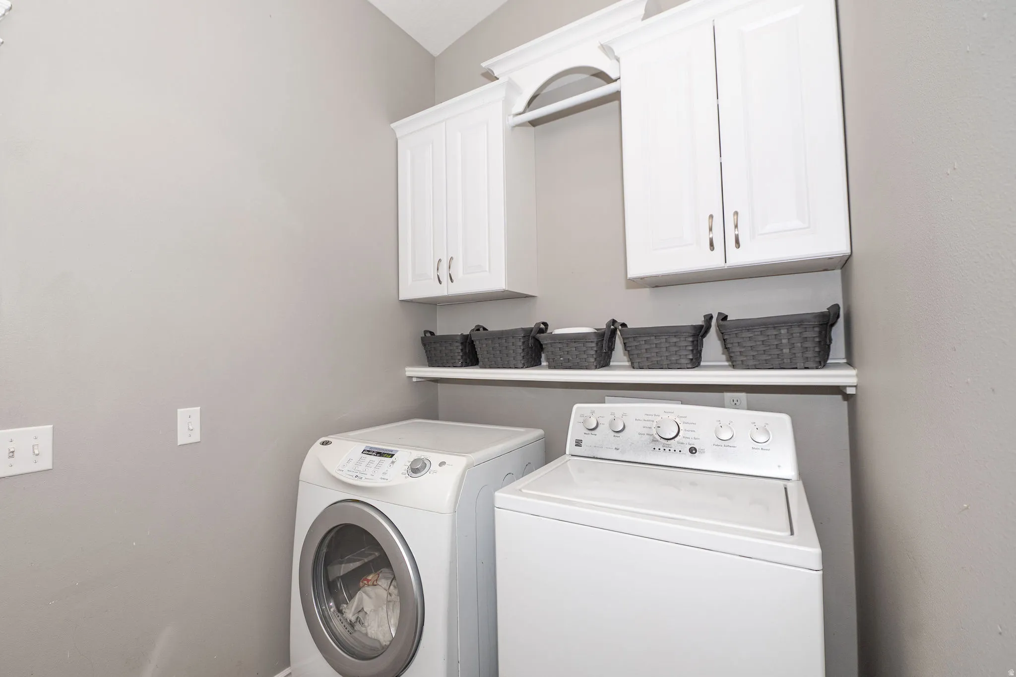 White shaker-style cabinetry with crown molding, a built-in hanging rod, and a floating storage shelf