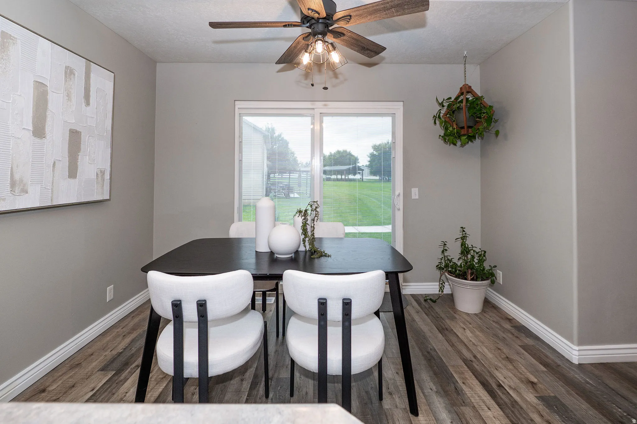 Wood-finish flooring, sliding glass door, ceiling fan with integrated lighting, and neutral wall tones