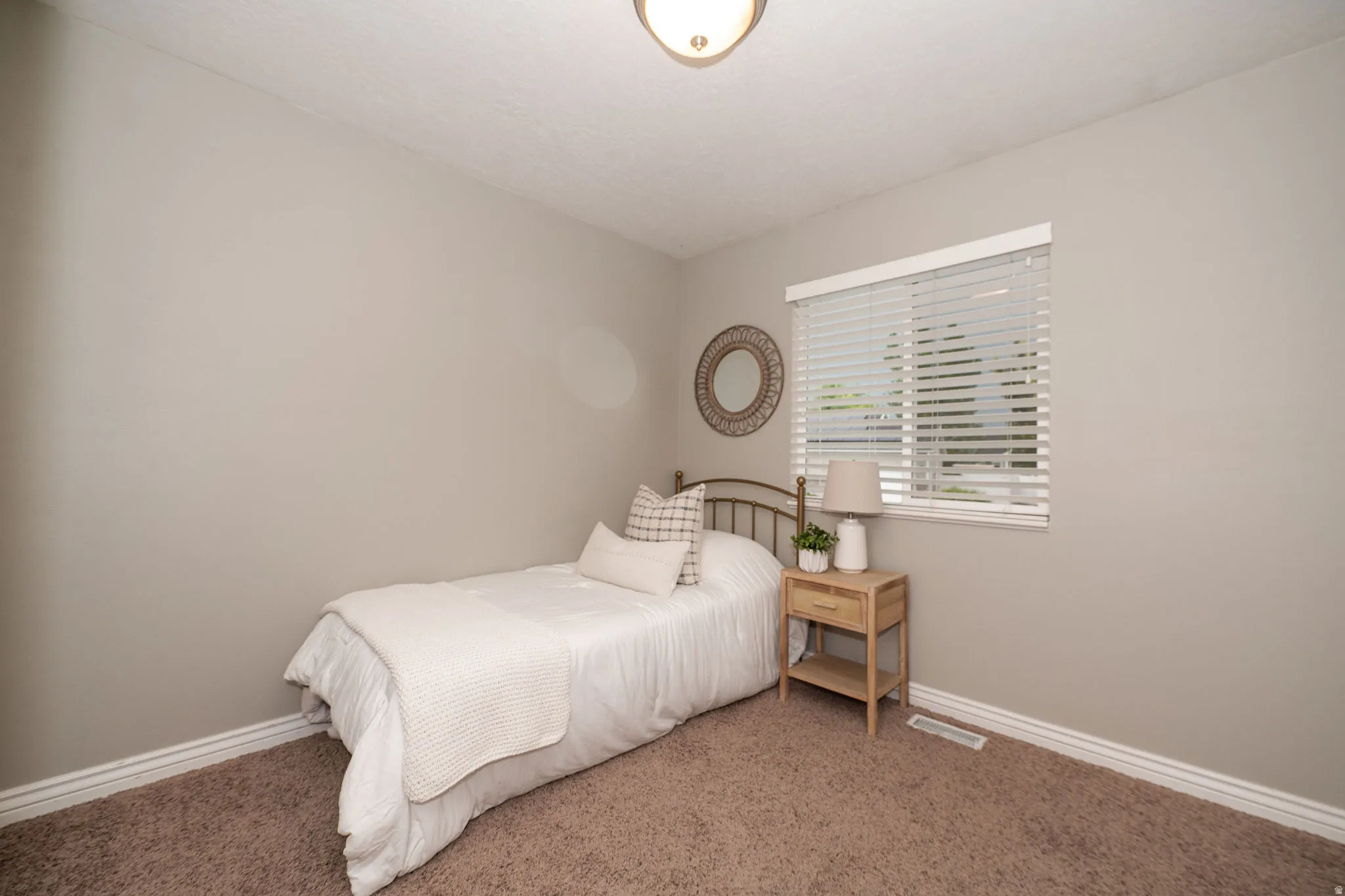 Textured carpet flooring, neutral painted walls, and a window with horizontal blinds