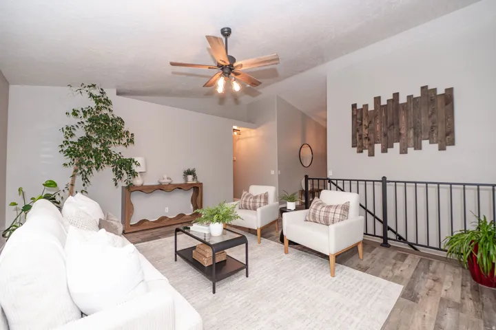 Wood-finish flooring, a ceiling fan with integrated lighting, and a console table with a decorative base