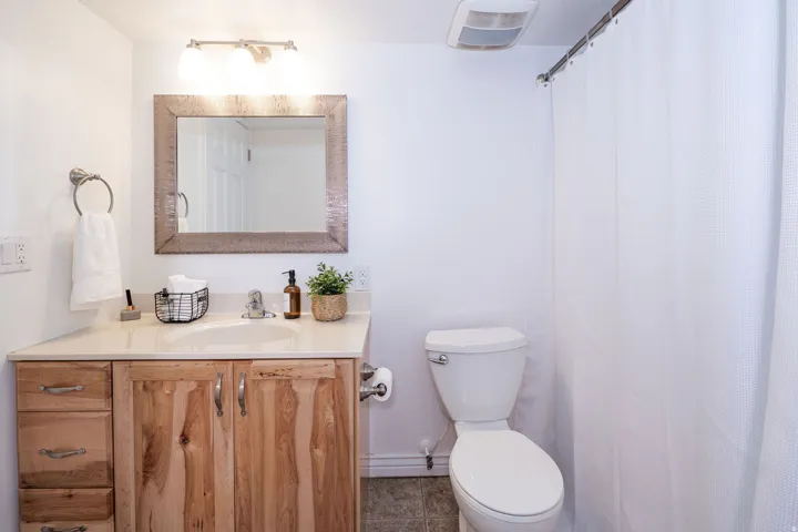Bathroom featuring a single vanity with wood-finish cabinetry, a built-in sink, and a light-toned countertop