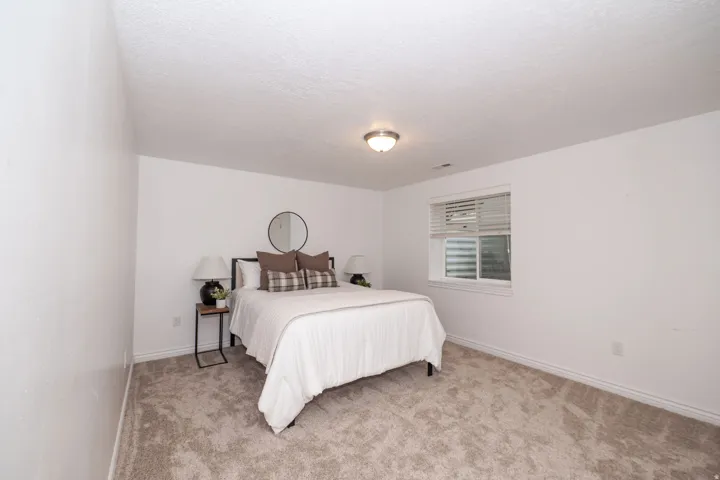 Wall-to-wall carpeting with light-toned walls and trim, featuring a flush-mount ceiling light and a window with blinds