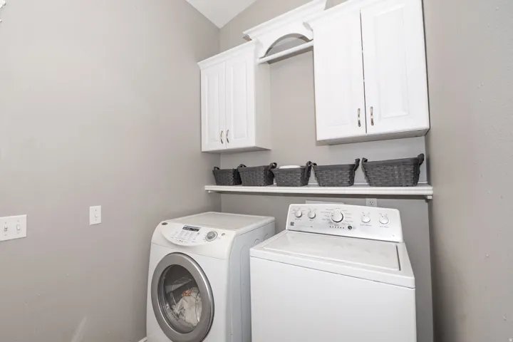 White shaker-style cabinetry with crown molding, a built-in hanging rod, and a floating storage shelf