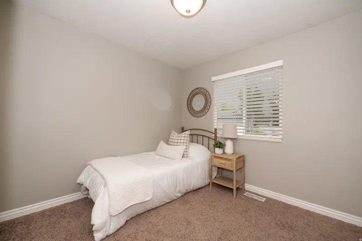 Textured carpet flooring, neutral painted walls, and a window with horizontal blinds
