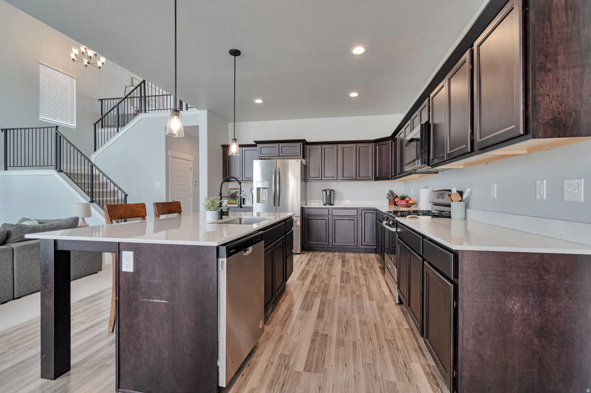 Spacious kitchen featuring dark wood cabinetry, light-toned countertops, and stainless steel appliances