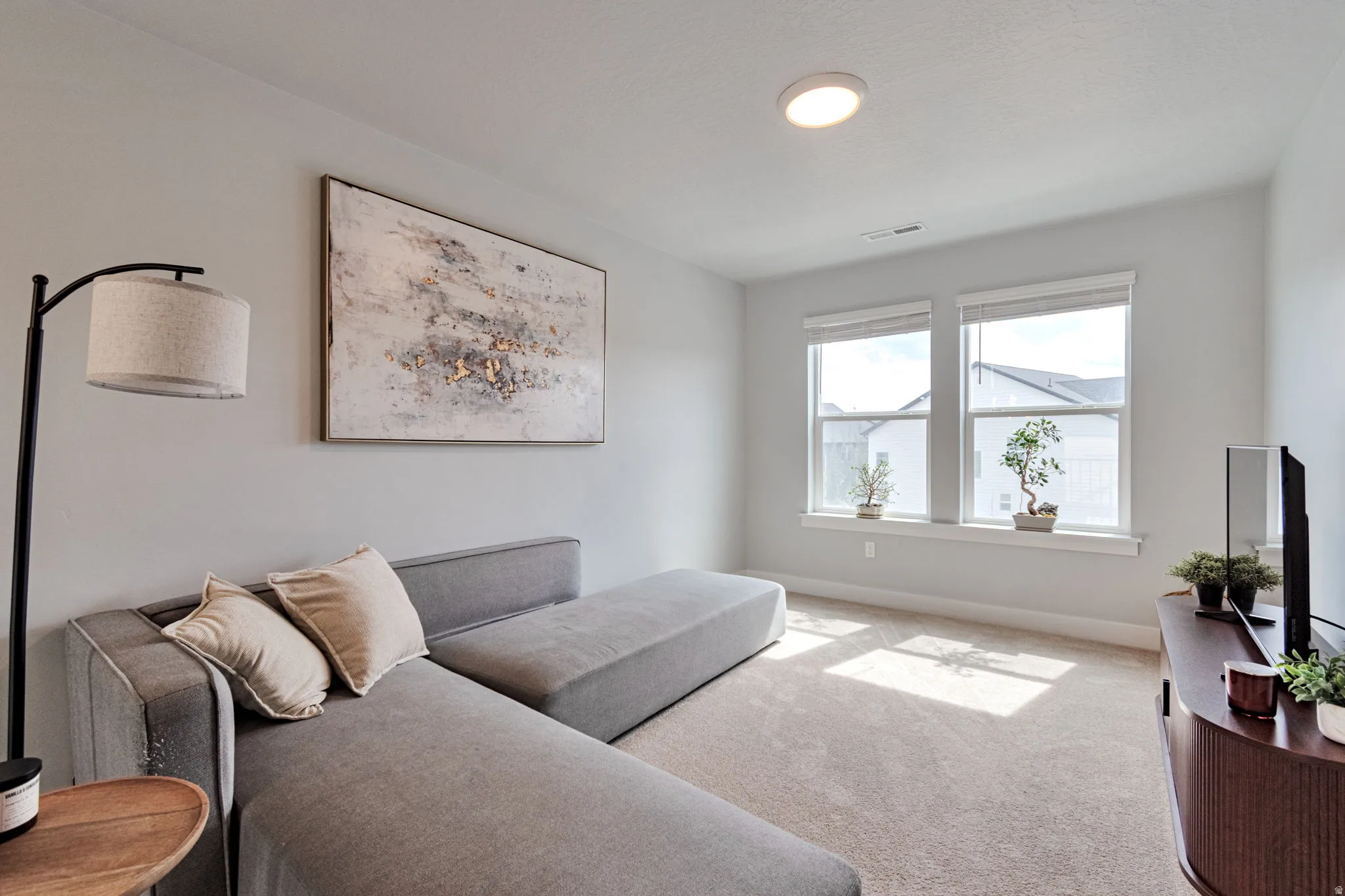 Recessed ceiling light with a flush-mount fixture, two large windows, light-colored carpeting, and light gray walls