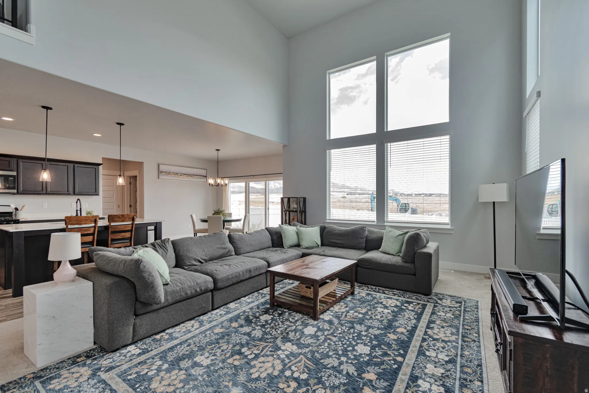 Living area featuring vaulted ceilings, a large window array, and an open-concept layout to the kitchen