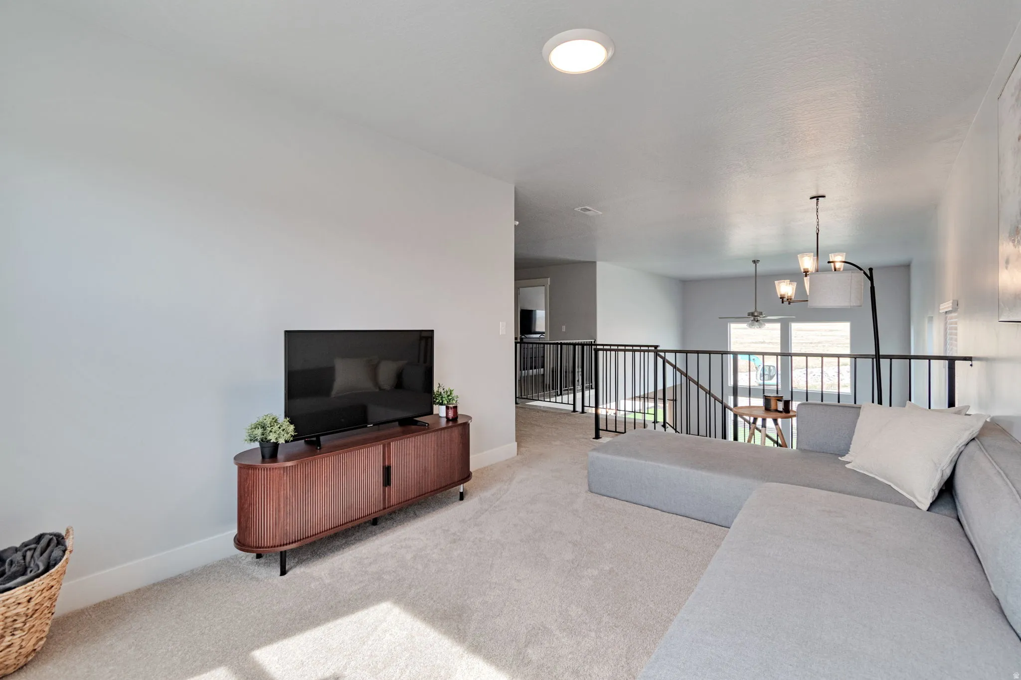 Carpeted loft space featuring an open railing, recessed lighting, and a chandelier