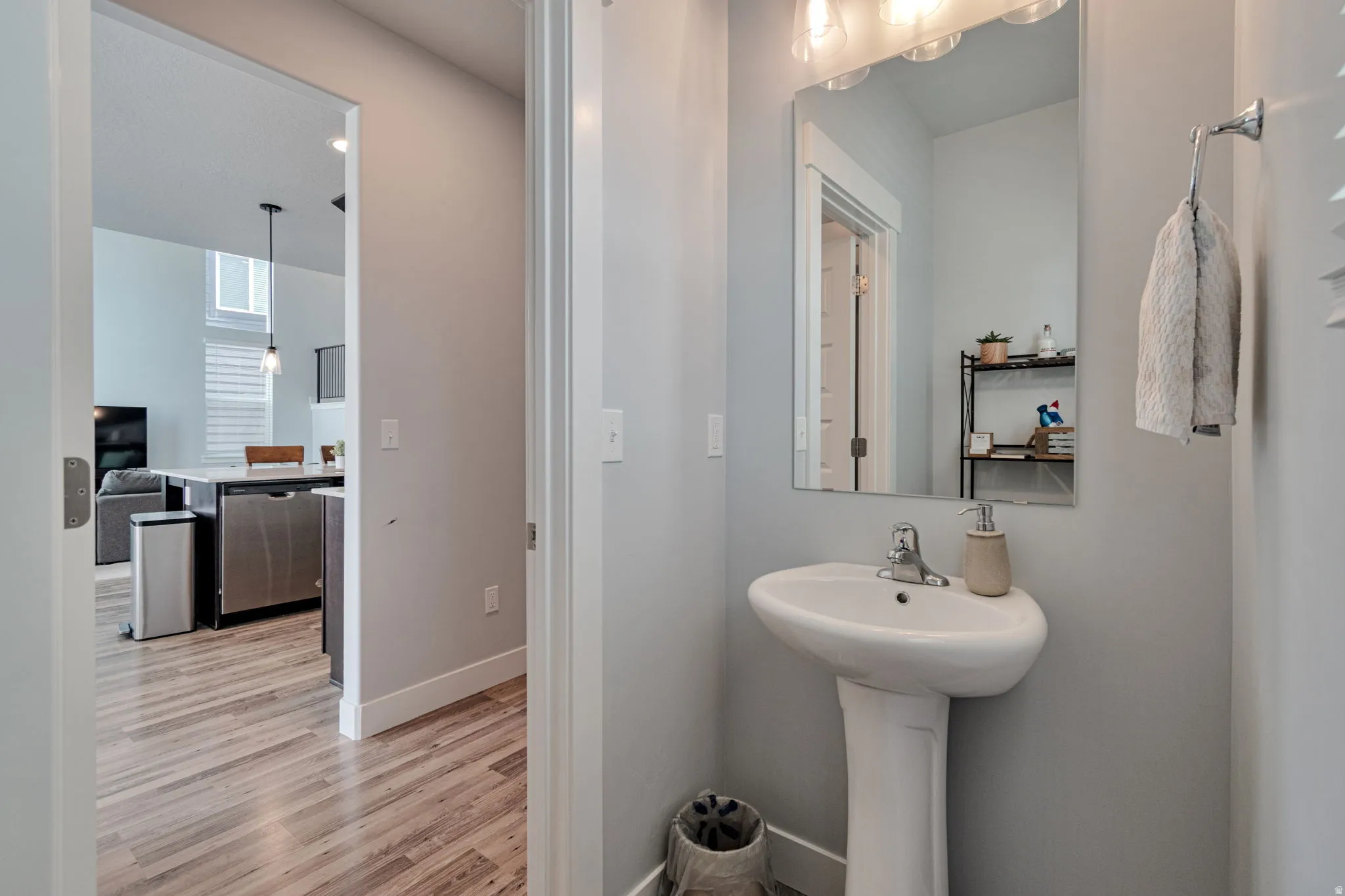 Pedestal sink with a polished chrome faucet, rectangular mirror, and wall-mounted vanity lighting