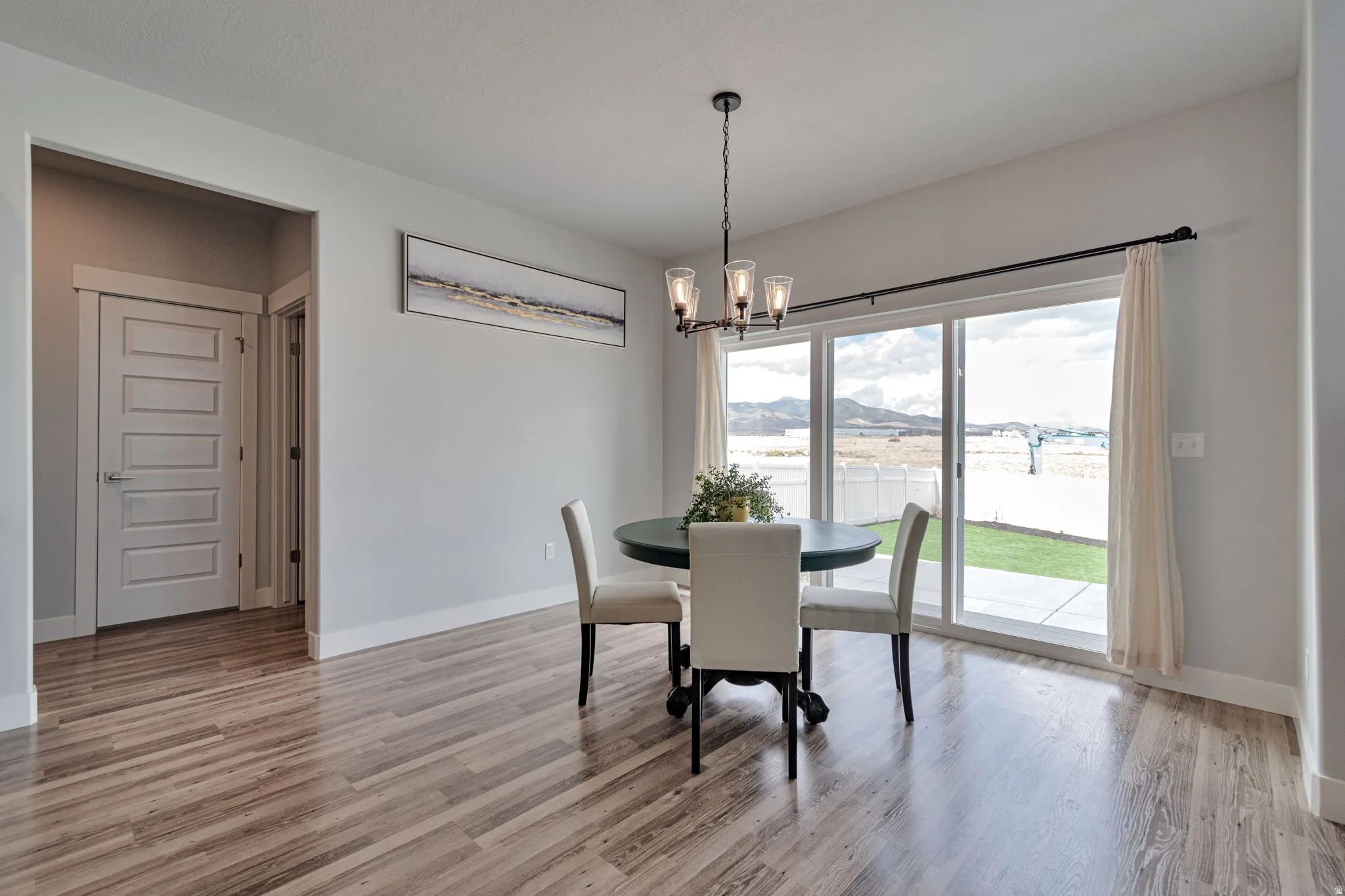 Wood-finish flooring, sliding glass door, and a multi-light chandelier