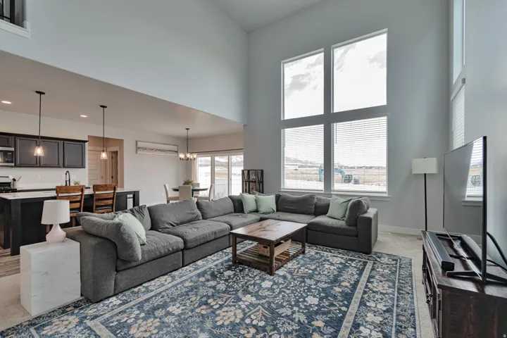 Living area featuring vaulted ceilings, a large window array, and an open-concept layout to the kitchen