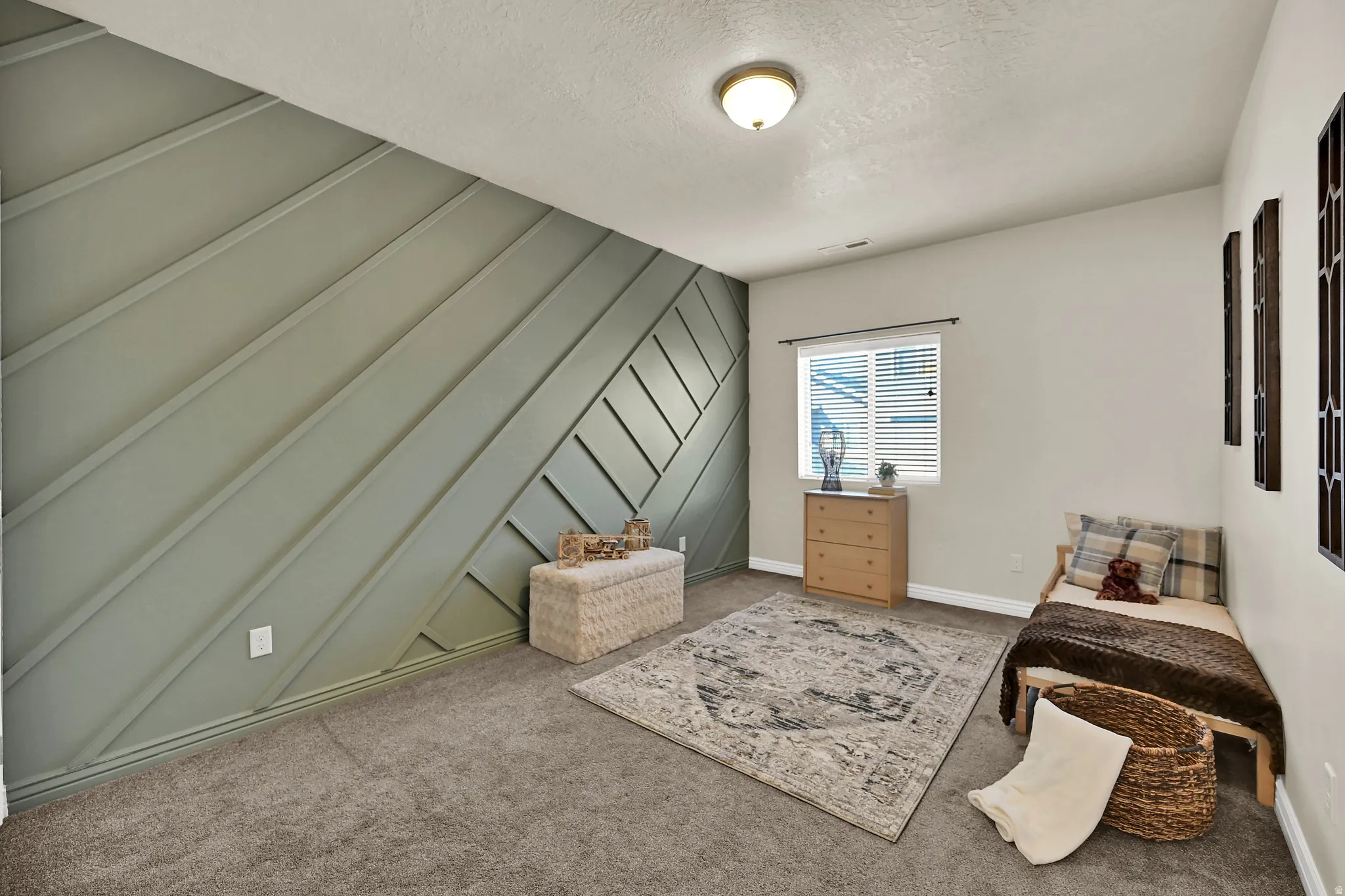 Accent wall with diagonal paneling, neutral wall paint, window with blinds, overhead flush mount light, and carpet flooring