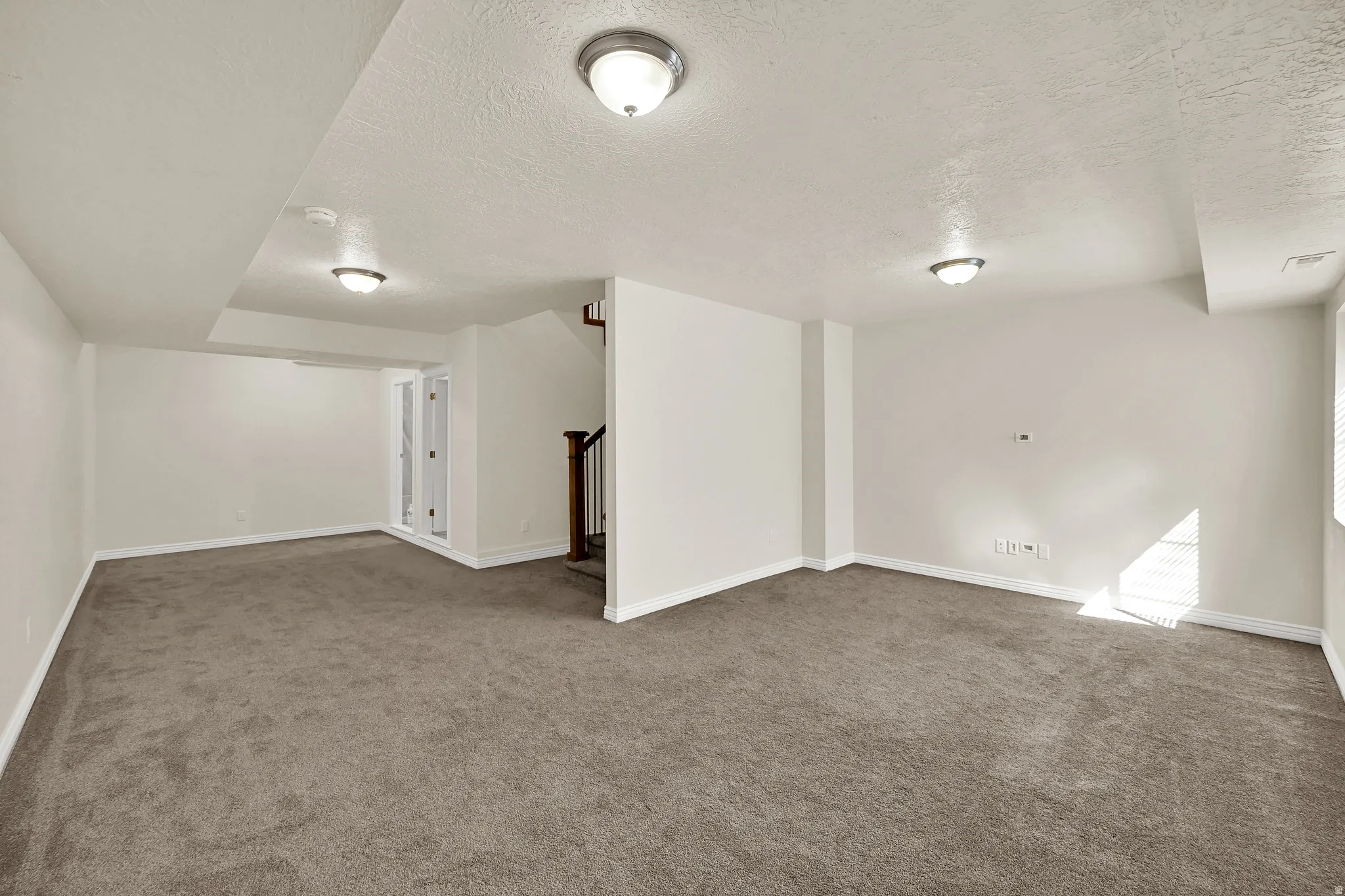 Expansive carpeted area with neutral wall finishes and recessed lighting
