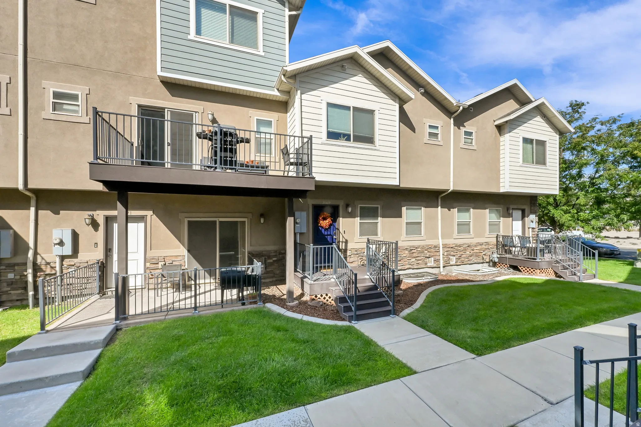 Multi-level exterior with a second-story balcony, ground-level patio, and stone veneer accents
