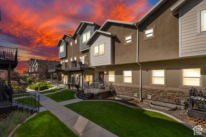 Townhome exterior with stone accent siding, private balconies, and landscaped grounds featuring manicured lawns and concrete pathways