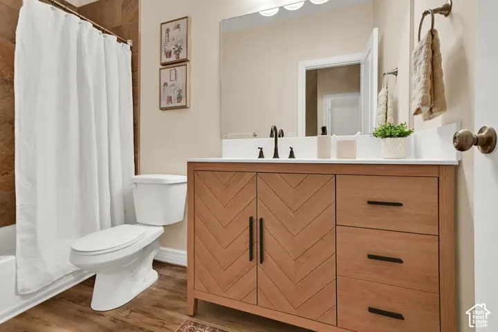Wood-finish flooring with a chevron-patterned vanity featuring a white countertop and integrated sink