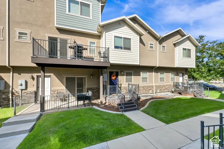 Multi-level exterior with a second-story balcony, ground-level patio, and stone veneer accents